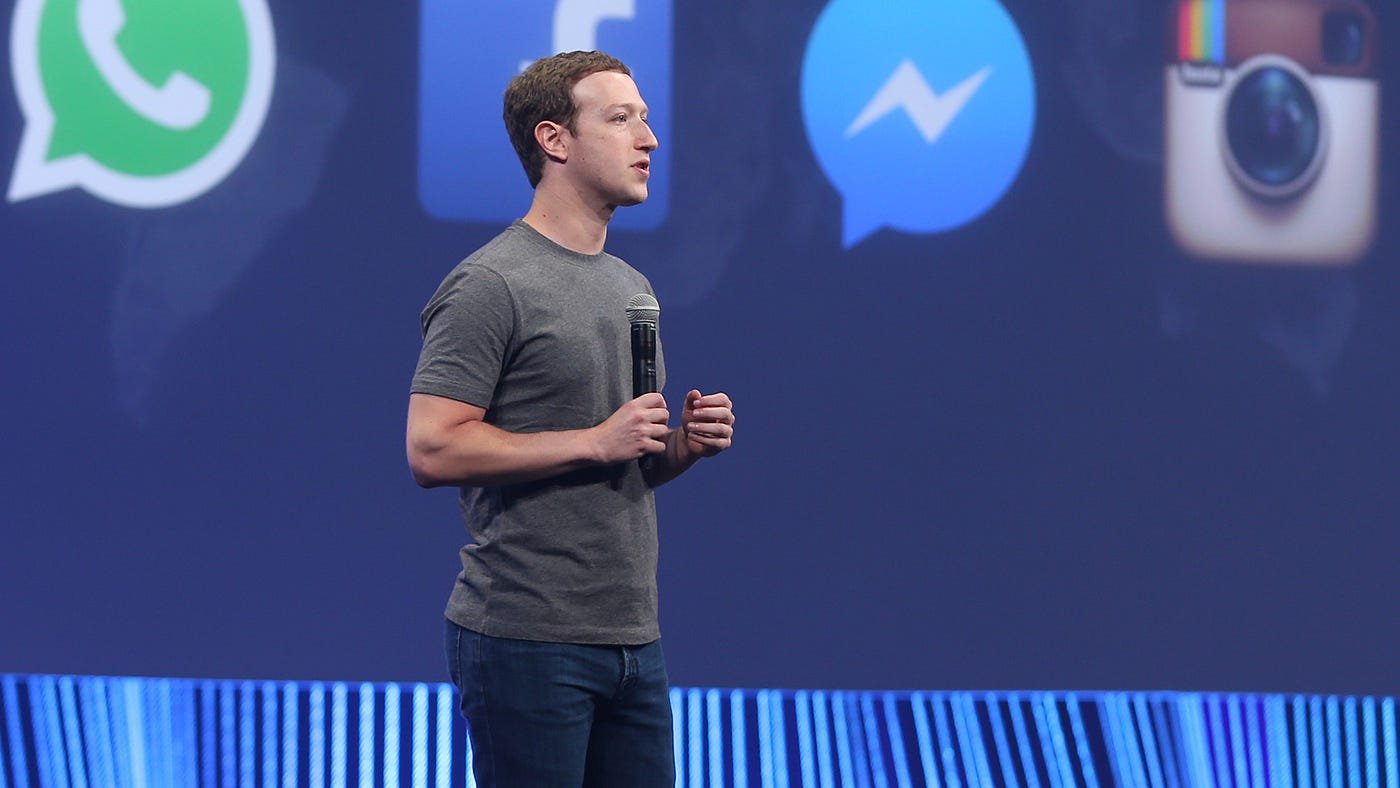 Mark Zuckerberg, Meta CEO, in grey shirt, presenting, holding a microphone in front of a backdrop of Facebook, Whatsapp, Instagram and Messenger logos. Whatsapp Monetization